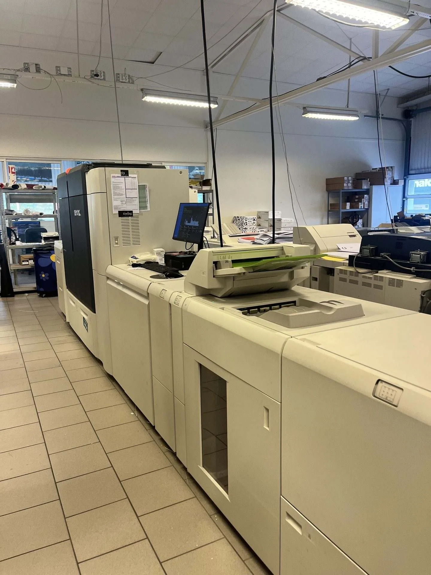 A modern printing facility featuring large printing machines and a computer workstation.